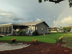 A house with a covered porch, a lawn, and a flag. - Coastal Coconut Cove near Anna Maria Island (Bradenton)
