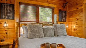 A wooden cabin bedroom with a bed, pillows, a tray with mugs, and framed diagrams on the walls. - Endless Views - King Beds - Close to attractions ! (Sevierville)
