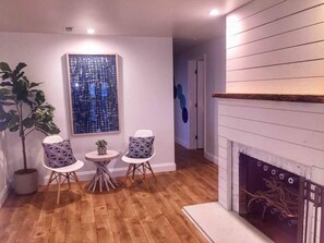 Un salón acogedor con suelo de madera, chimenea y un cuadro abstracto moderno.