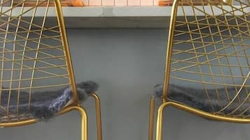 A kitchen with two gold wire chairs, a white cabinet, and a tiled backsplash.