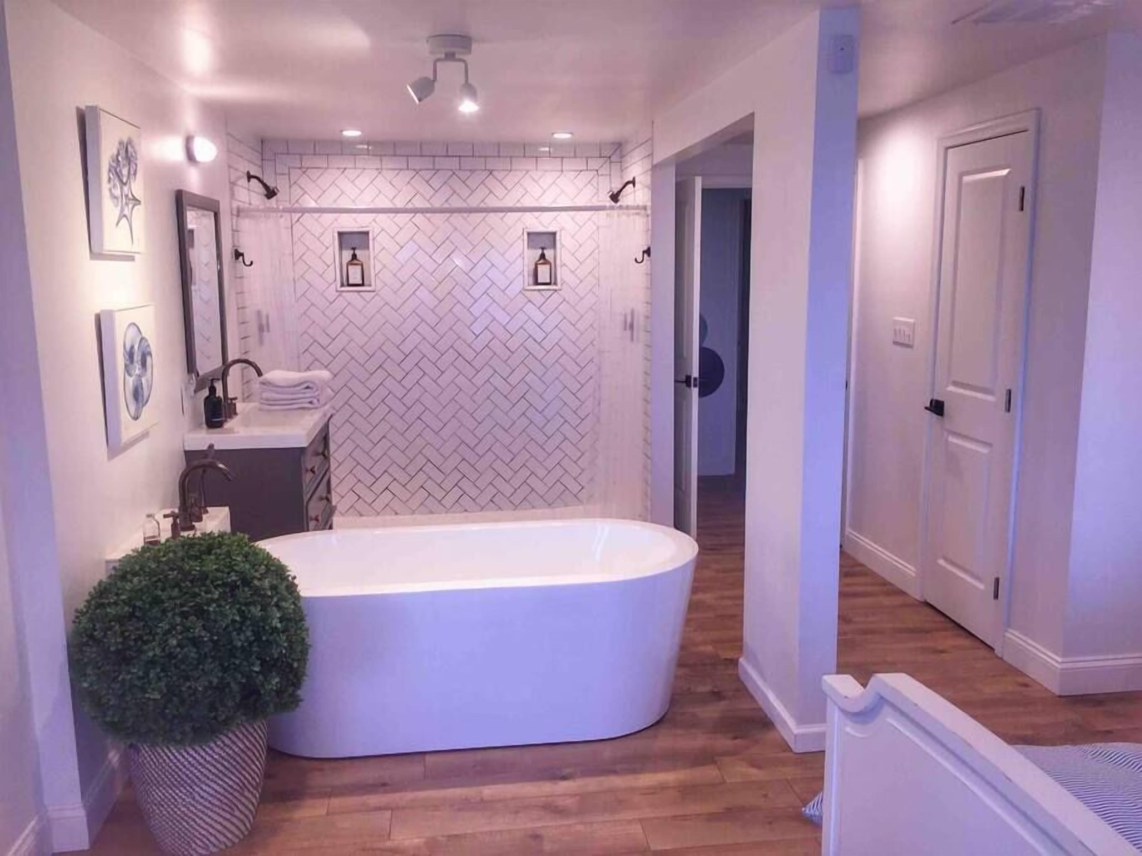 A modern bathroom with a freestanding bathtub, a sink with a mirror, and a potted plant.