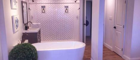 A modern bathroom with a freestanding bathtub, a sink with a mirror, and a potted plant.