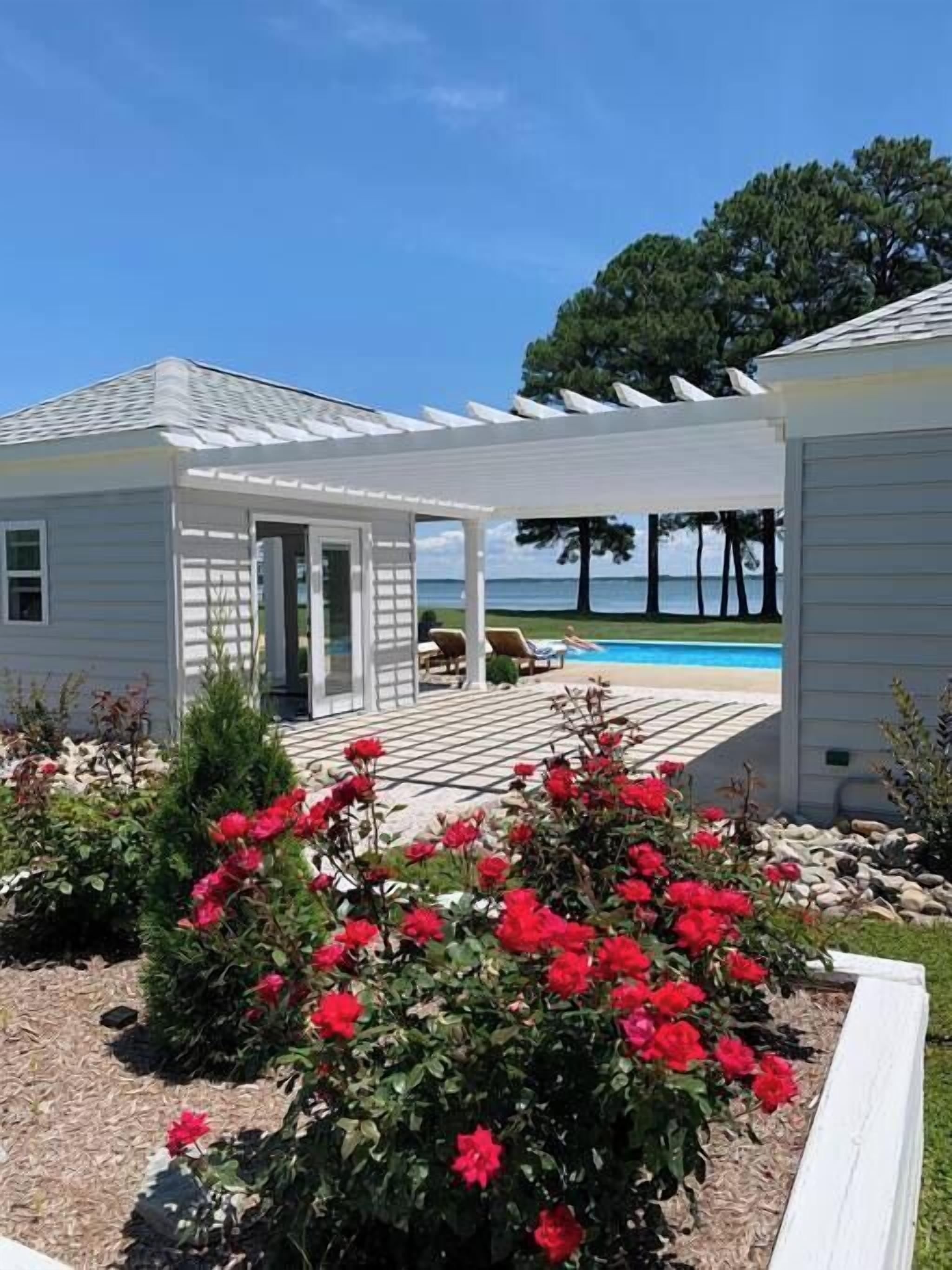 A house with a covered patio, a swimming pool, and a view of the ocean.
