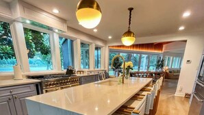 A spacious kitchen with a large island, wooden flooring, and pendant lighting. - Thorneton Point Estate (Easton)