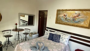 Un dormitorio con cama, escritorio, silla, espejo y un cuadro en la pared.