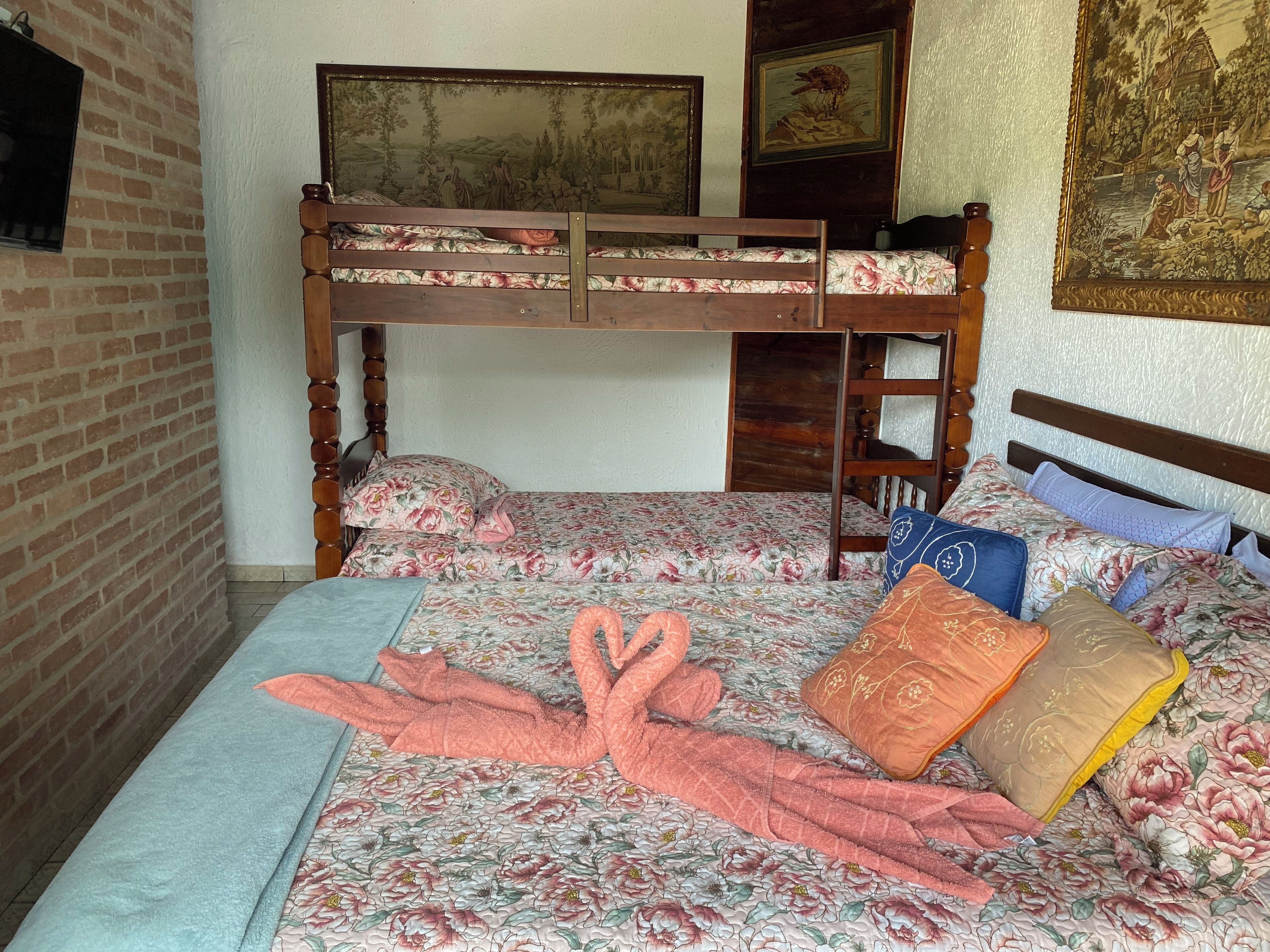 Ein Etagenbett mit Blumenmuster-Bettwäsche, einem Holzkopfstück und einer Ziegelwand.