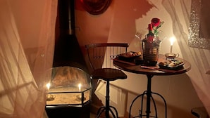 Una habitación acogedora con una mesa dispuesta para comer, una vela y un florero decorativo con una rosa.