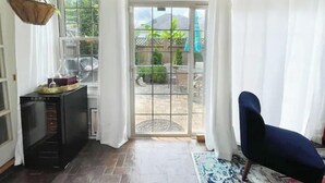 A room with a sliding glass door leading to a patio, a dark-colored sofa, and a hanging plant. - Lovely 3 Bdrm Home w/Free Parking Close to I-75! (Lexington)