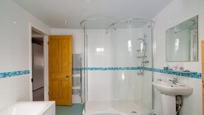 Un bagno moderno con doccia vetrata, lavandino bianco e vasca da bagno.