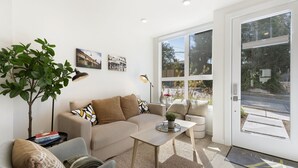 A modern living room with a sofa, coffee table, and a large window providing a view of the outdoors. - Cheerful 3-bedroom New Townhouse near UW/Seattle Children's, Free Parking, AC (Seattle)