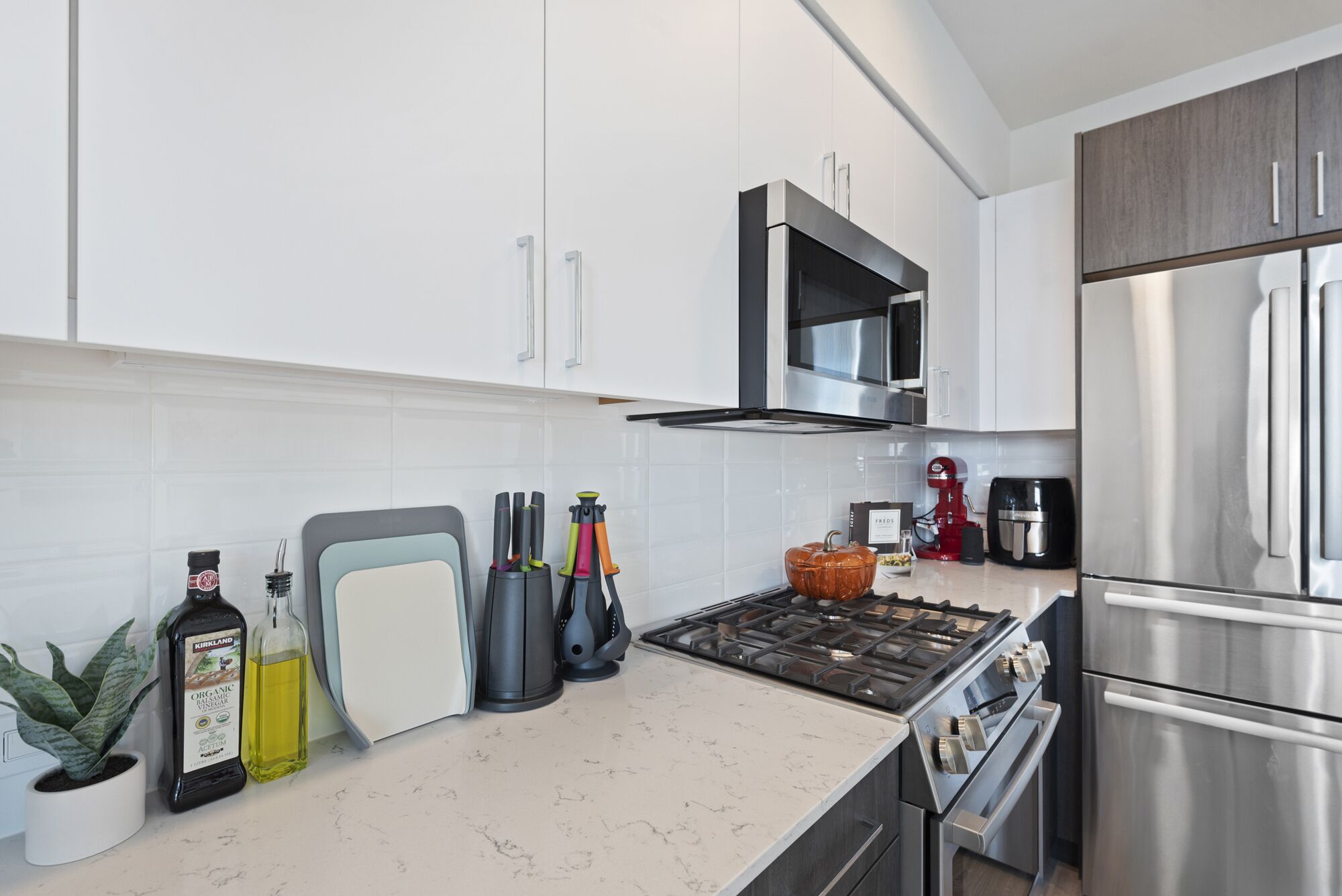 Een moderne keuken met witte kasten, roestvrijstalen apparatuur en een marmeren aanrecht.