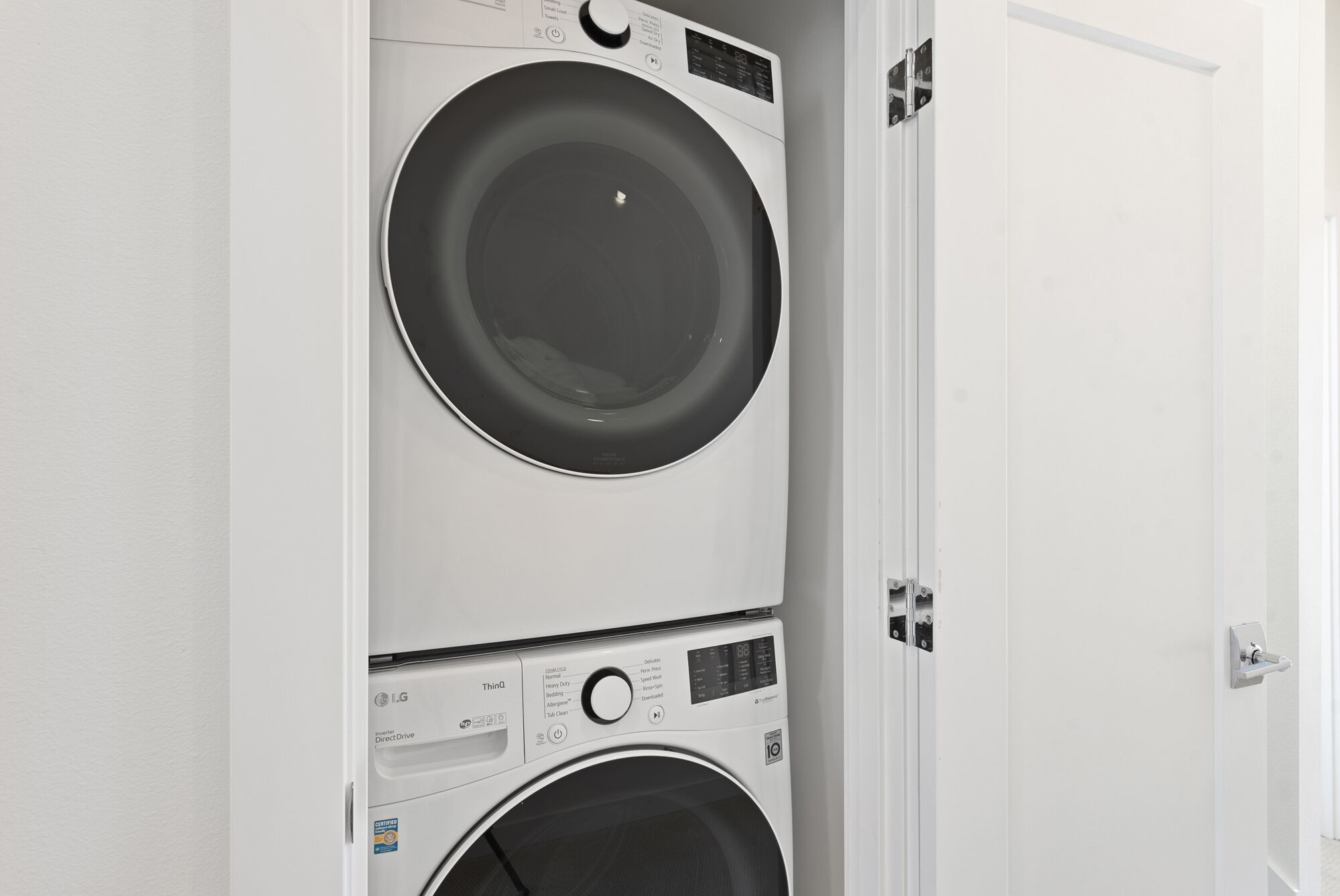 Una lavadora y secadora apiladas en una habitación con paredes blancas.