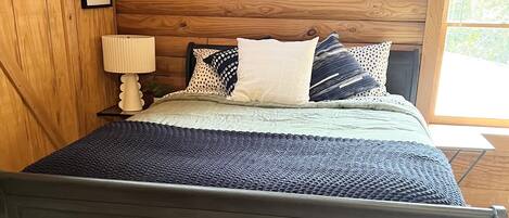 Una habitación con paneles de madera, una cama, aire acondicionado de pared y fotografías enmarcadas.