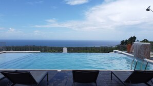 A pool with a view of the ocean, surrounded by a fence and a few lounge chairs. - Ocho Rios Heights Ultra Lux Villa (Ocho Rios)