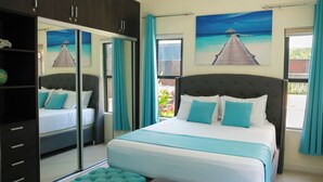 A bedroom with a large bed, a wardrobe, and a view of the beach through the window. - Ocho Rios Heights Ultra Lux Villa (Ocho Rios)