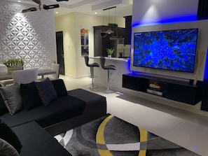 Een moderne woonkamer met een hoekbank, een flatscreen televisie en een decoratieve wand.