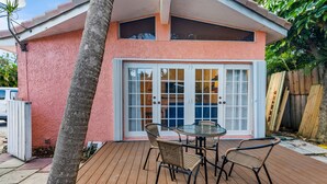 A pink house with a deck, a glass door, and a table with chairs. - Coco Bay Condos (Fort Lauderdale)