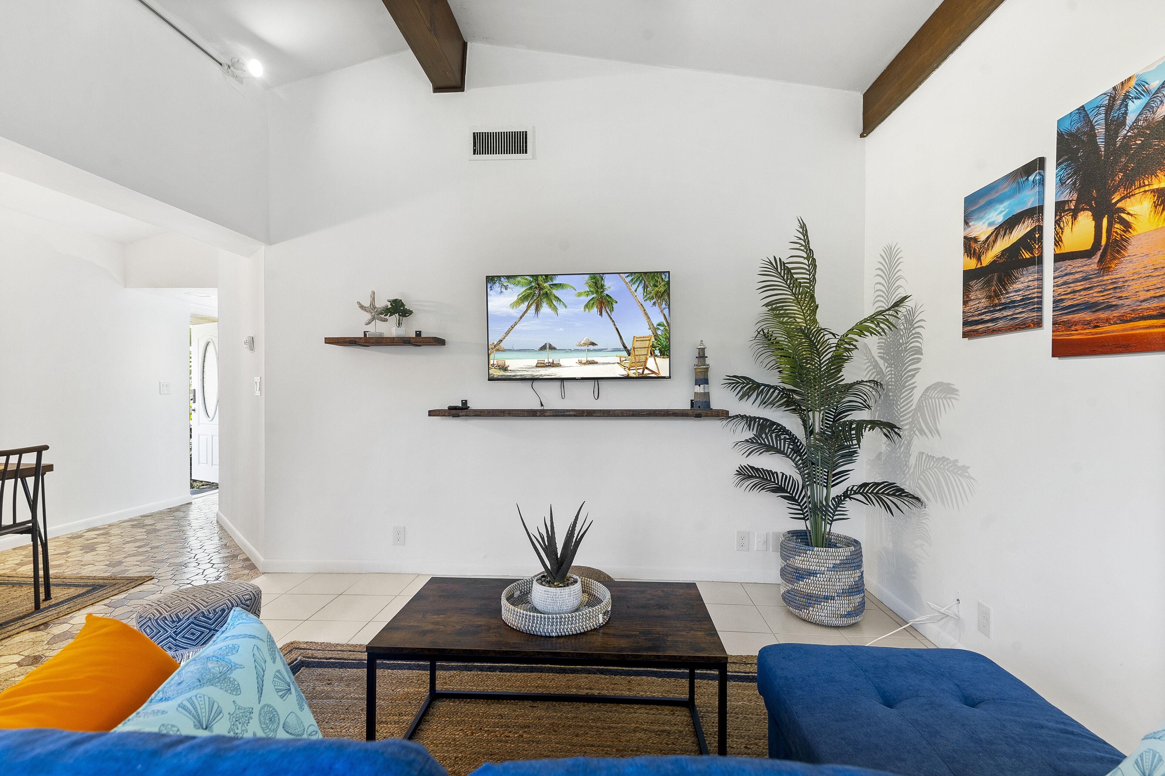 A living room with a TV, a sofa, a coffee table, and a potted plant.