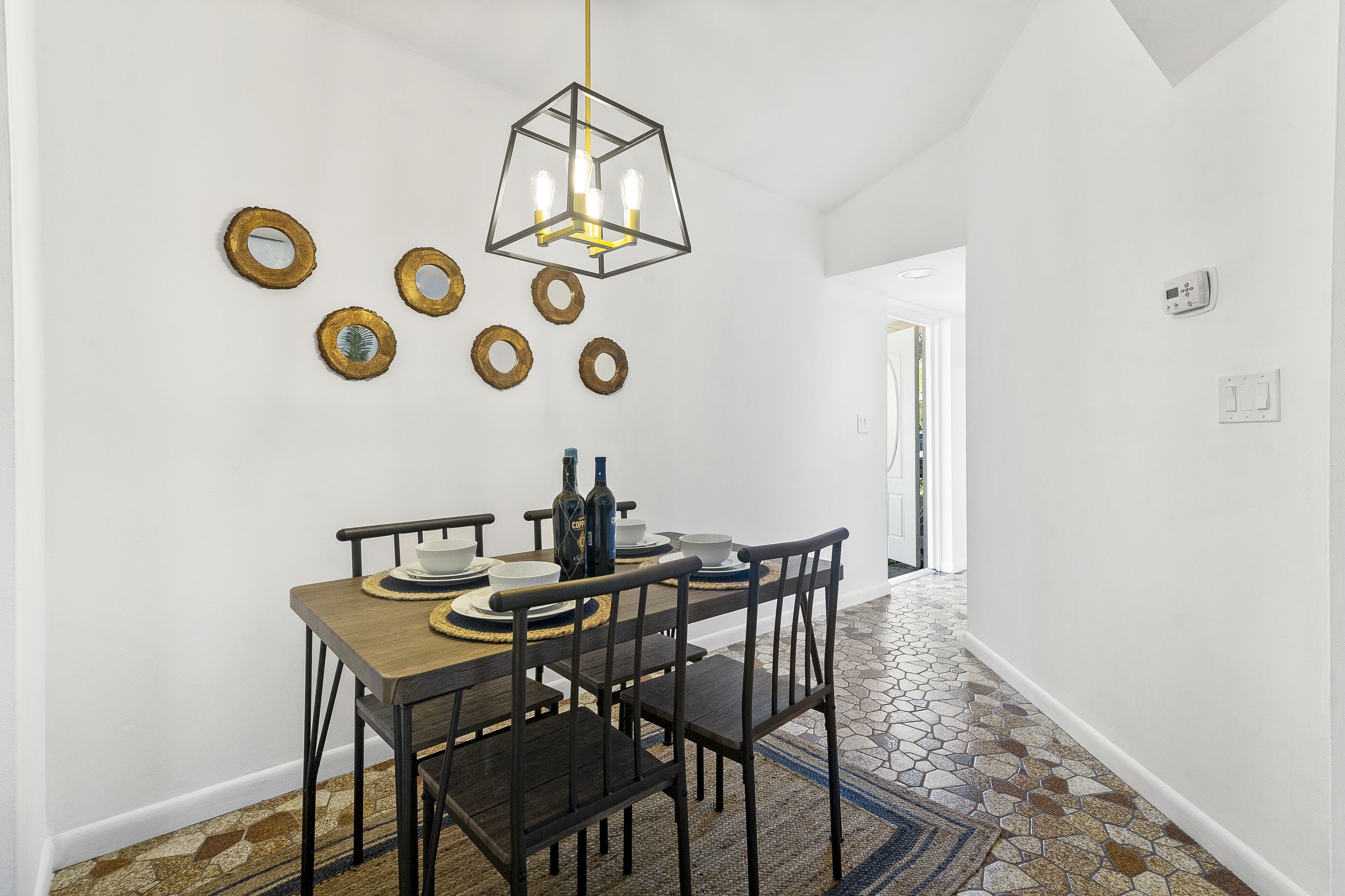 Un comedor con mesa de madera, sillas negras y una lámpara colgante.