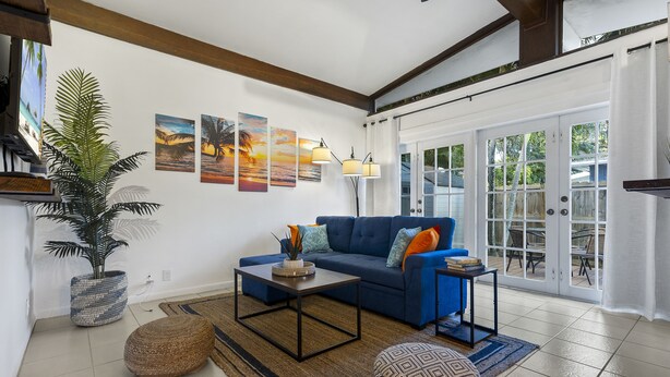 A living room with a blue sofa, a coffee table, a potted plant, and artwork on the wall. - Coco Bay Condos (Fort Lauderdale)