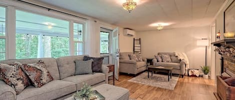 A spacious living room with a grey sofa, two armchairs, a coffee table, and a fireplace.
