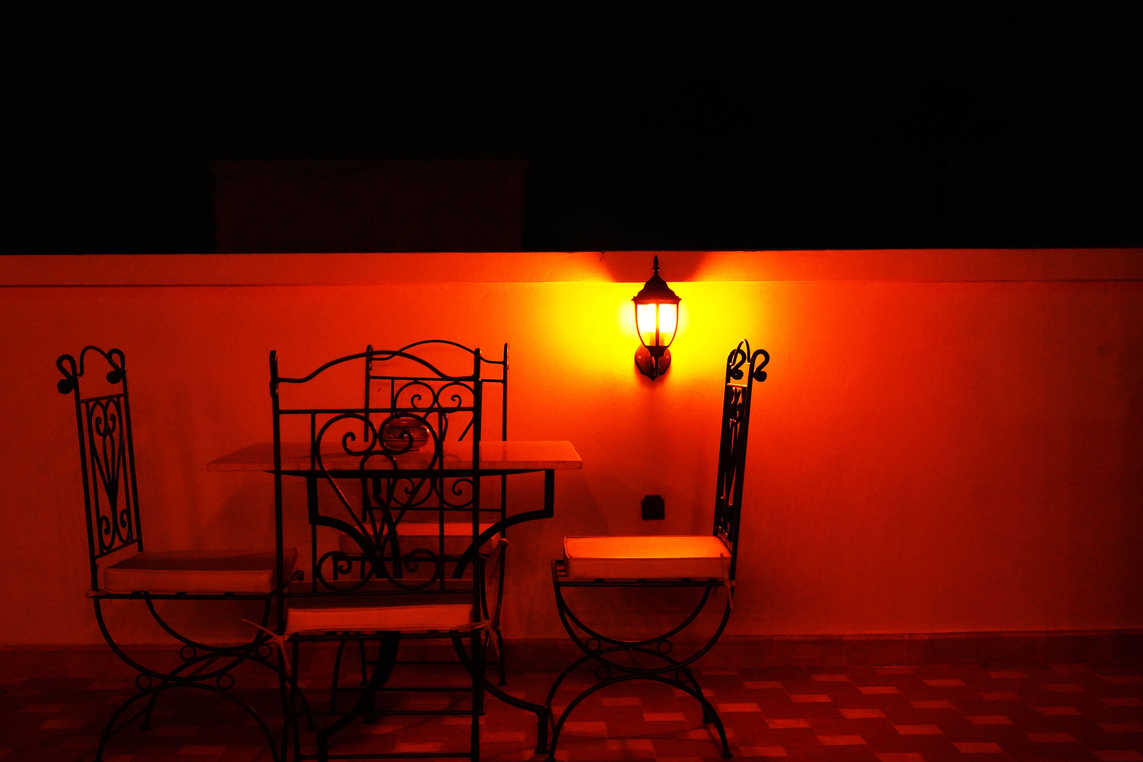 A table and chairs with a wall-mounted light fixture.
