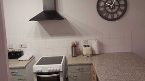Une cuisine équipée d’une cuisinière, d’un four et d’une horloge murale.