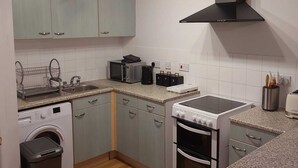 Une cuisine compacte équipée d’un lave-linge, d’un four à micro-ondes, d’une cuisinière et d’un évier.