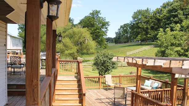 A wooden deck with outdoor furniture, a pergola, and a view of a grassy field and trees. - Family Friendly Home w/ Large 1 Acre Backyard & Decks (Peach Bottom)