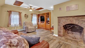 A cozy living room with a fireplace, wooden shelves, and a comfortable chair. - Family Friendly Home w/ Large 1 Acre Backyard & Decks (Peach Bottom)