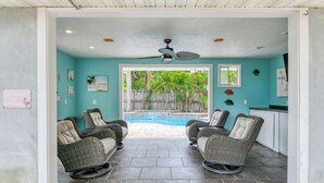 Ein Zimmer mit Pool, Korbstühlen, Deckenventilator und Blick auf den Garten.
