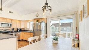 Een moderne keuken met houten kastjes, roestvrijstalen apparatuur en een eetgedeelte met een houten tafel en stoelen.