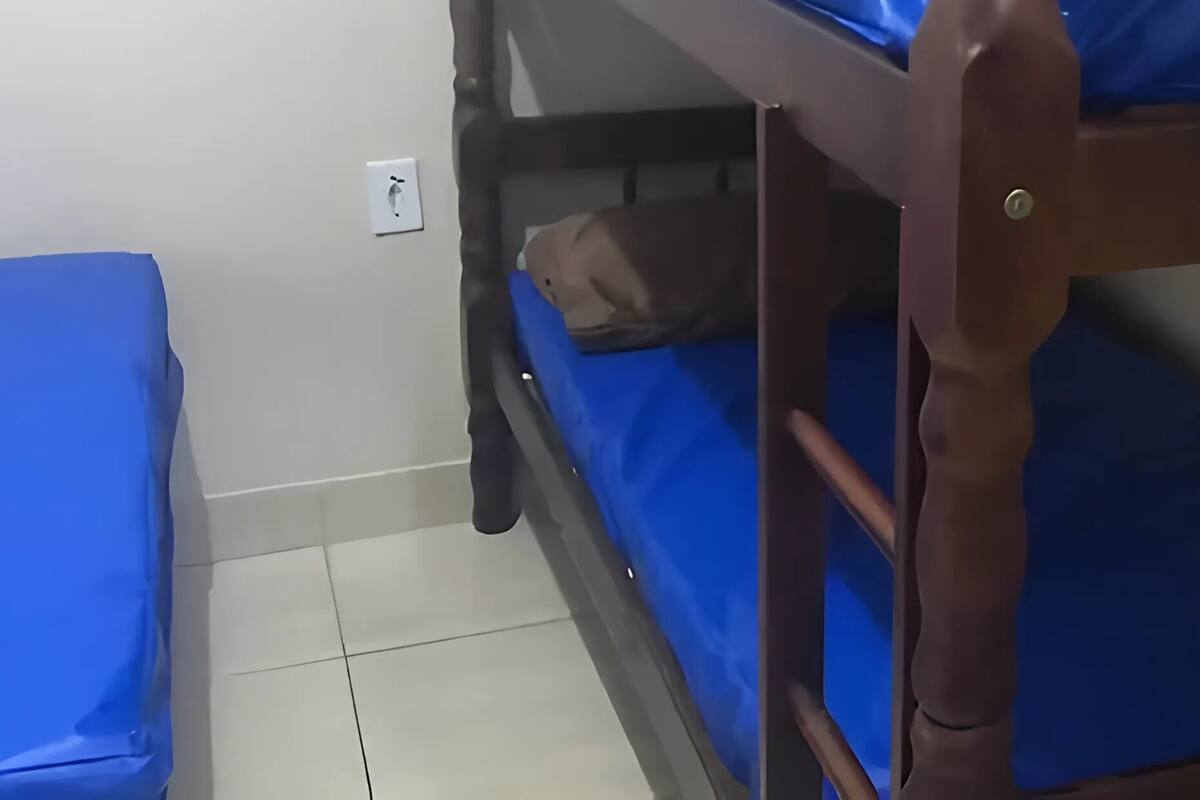 A bunk bed with blue bedding and a small bag on the lower bunk.