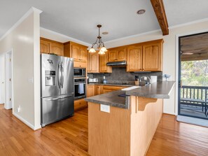 A modern kitchen with wooden cabinets, stainless steel appliances, and a large island.
