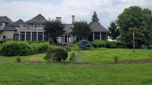 A large, two-story house with a spacious front yard, a covered porch, and a well-maintained lawn.