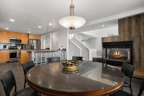 Una cocina moderna con una isla central, electrodomésticos de acero inoxidable y un comedor con una mesa redonda y sillas.