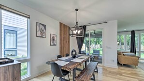 Un comedor moderno con una mesa de madera, sillas negras y una lámpara colgante.