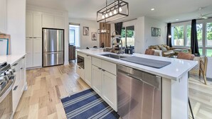 Una cocina moderna con electrodomésticos de acero inoxidable, una isla grande y un comedor con sofá y mesa.