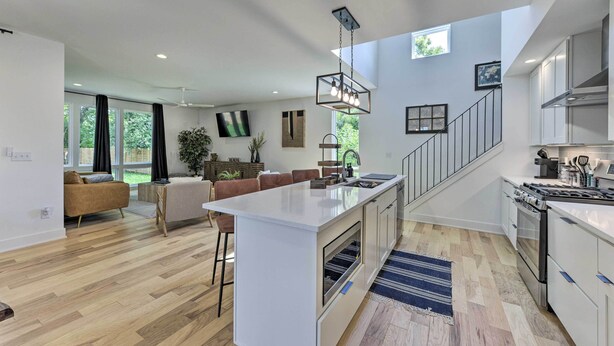 Una cocina moderna con una isla central, armarios blancos y una campana extractora de acero inoxidable.