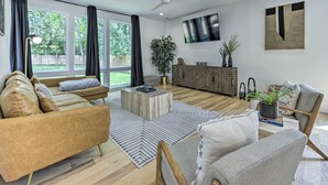 Una sala de estar moderna con un sofá, sillones, una mesa de centro y un televisor montado en la pared.