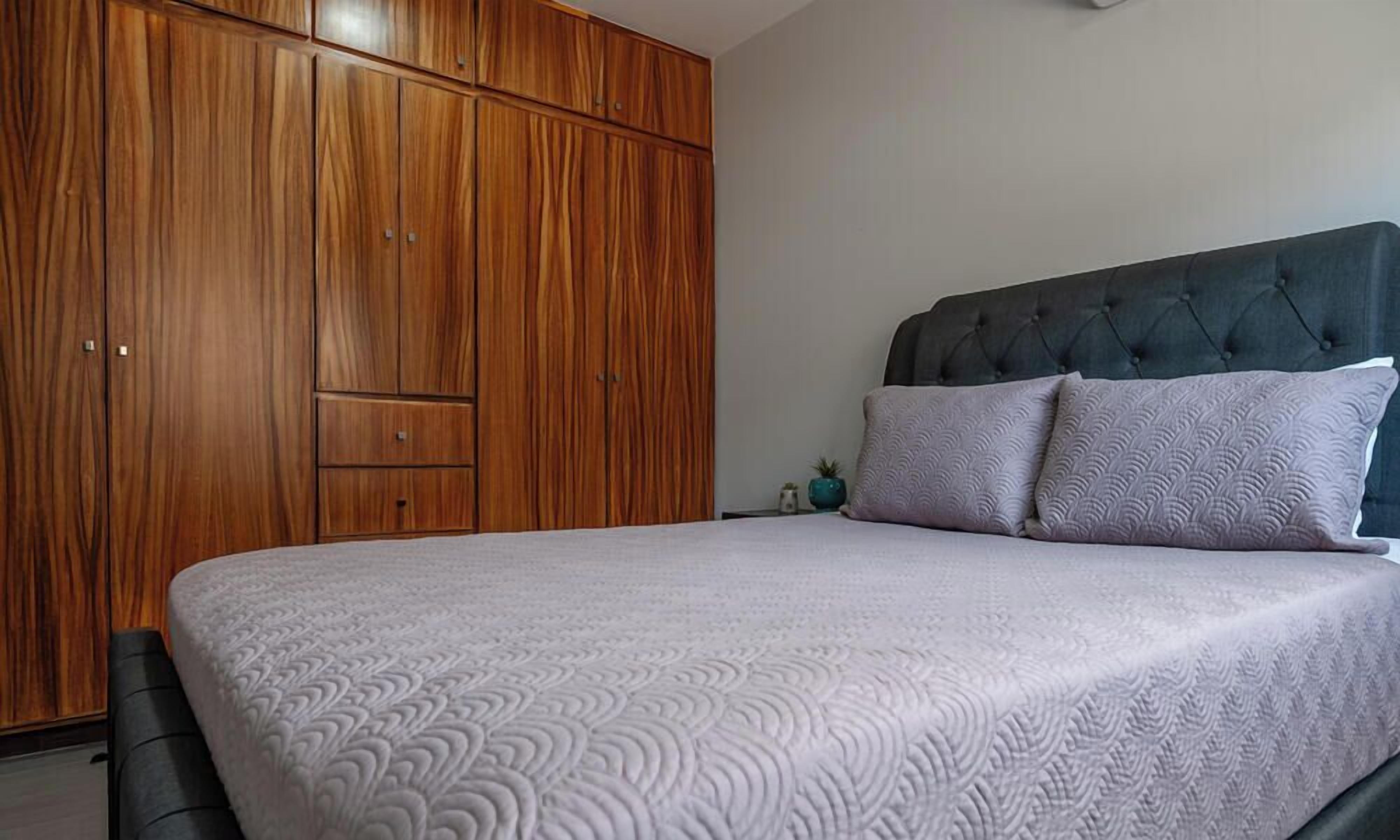 Un dormitorio con cama, armario y cabecero.