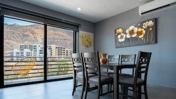 Un comedor con una mesa y sillas, una ventana que ofrece vistas a edificios y un cuadro en la pared.