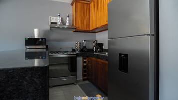 Una cocina con electrodomésticos de acero inoxidable, gabinetes de madera y una encimera.
