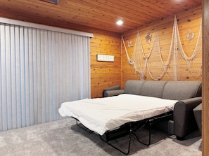 Une pièce comprenant un lit, un canapé, un plafond en bois et un mur orné de décorations suspendues.