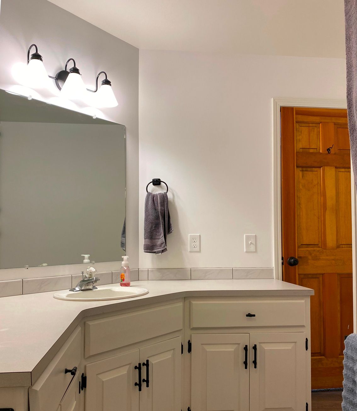 Une salle de bain moderne avec un grand meuble-lavabo, un miroir et trois appliques murales.