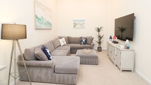 A living room with a sectional sofa, a floor lamp, a television, and a cabinet with decorative items. - New Listing! Beautiful 2000 Square Foot Multi-Level Townhome. 1 BLOCK FROM BEACH (Seaside Heights)