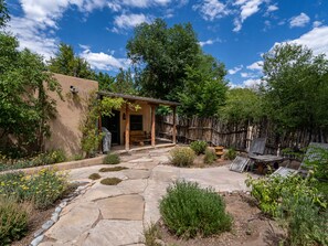 Un patio con pérgola, sendero de piedra y mobiliario exterior.