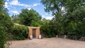 Un espace extérieur rustique agrémenté d’une porte en bois, de deux grands jardinières et d’un chemin de gravier menant à la porte.