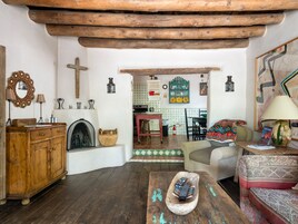 Una sala rústica con muebles de madera, chimenea y vista al área de la cocina.