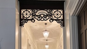 A hallway with white walls, wooden floors, and a decorative black metal ceiling.